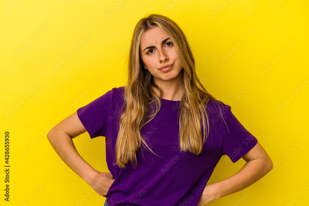 Young blonde caucasian woman isolated on yellow background confused, feels doubtful and unsure. Young blonde caucasian woman isolated on yellow background confused, feels doubtful and unsure.