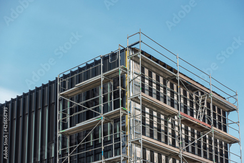 Construction of a modern office building with scaffolding against blue sky