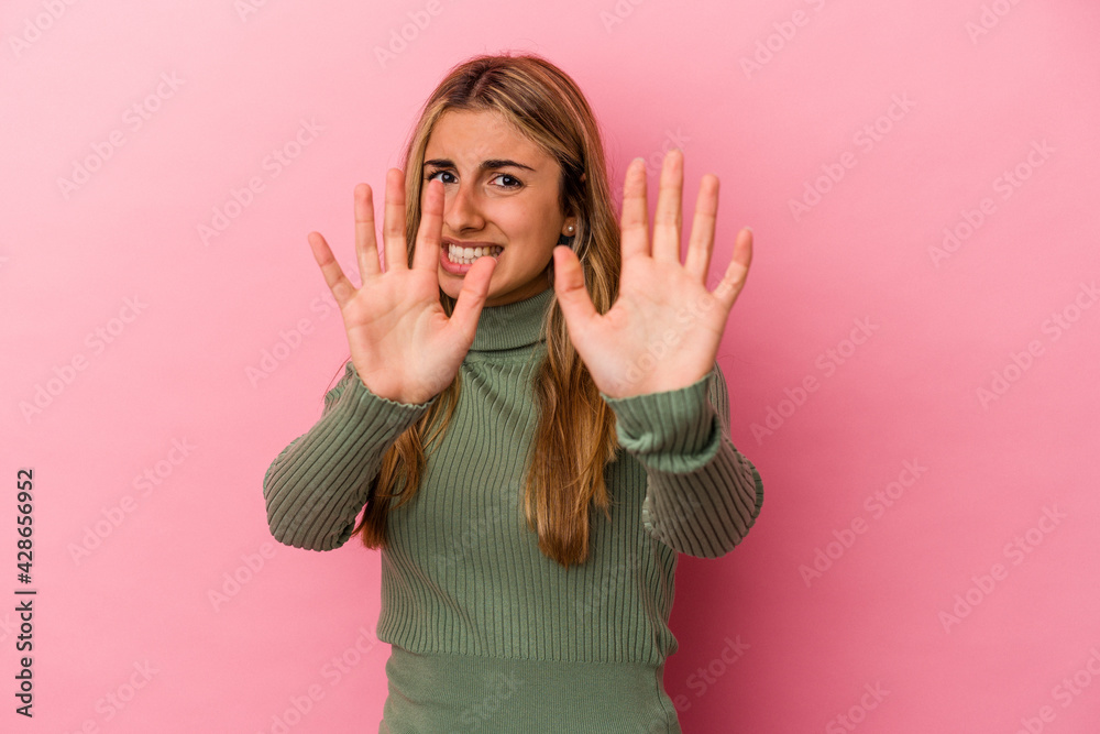 Young blonde caucasian woman isolated on pink background rejecting someone showing a gesture of disgust. Young blonde caucasian woman isolated on pink background rejecting someone showing a gesture of disgust.