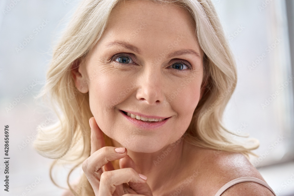 Adult senior older woman touching perfect soft face skin with hand