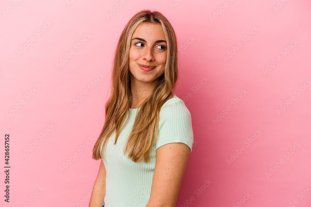 Young blonde caucasian woman isolated on pink background looks aside smiling, cheerful and pleasant. Young blonde caucasian woman isolated on pink background looks aside smiling, cheerful and pleasant.