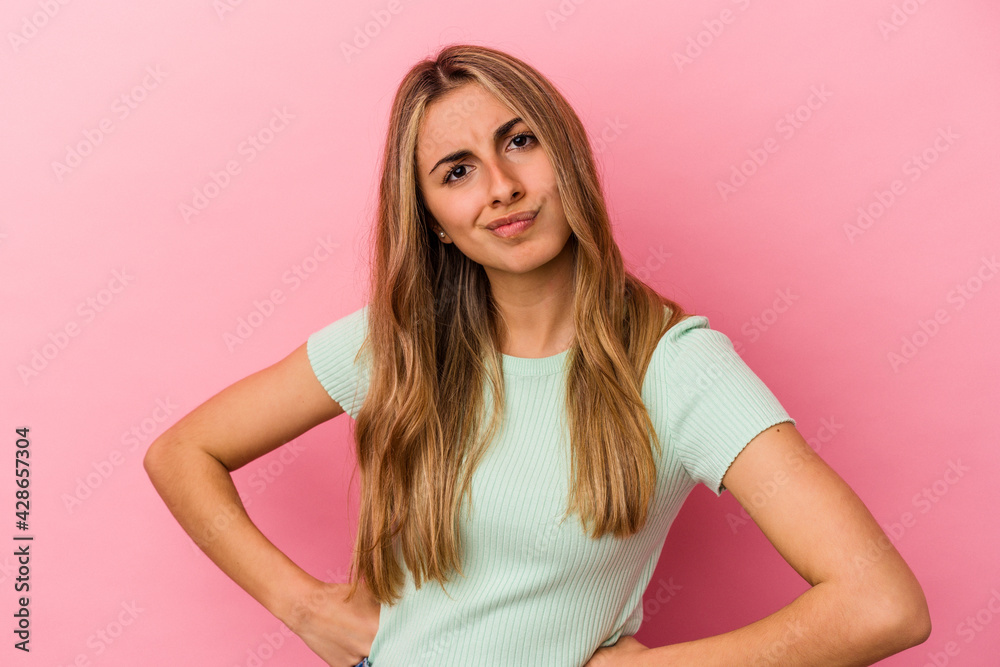 Young blonde caucasian woman isolated on pink background frowning face in displeasure, keeps arms folded. Young blonde caucasian woman isolated on pink background frowning face in displeasure, keeps arms folded.