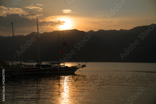 Beautiful Sunset over the sea and mountains. Sailing boats in the sea in the foreground.