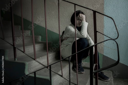 Sad girl sitting on the stairs at the entrance of the house