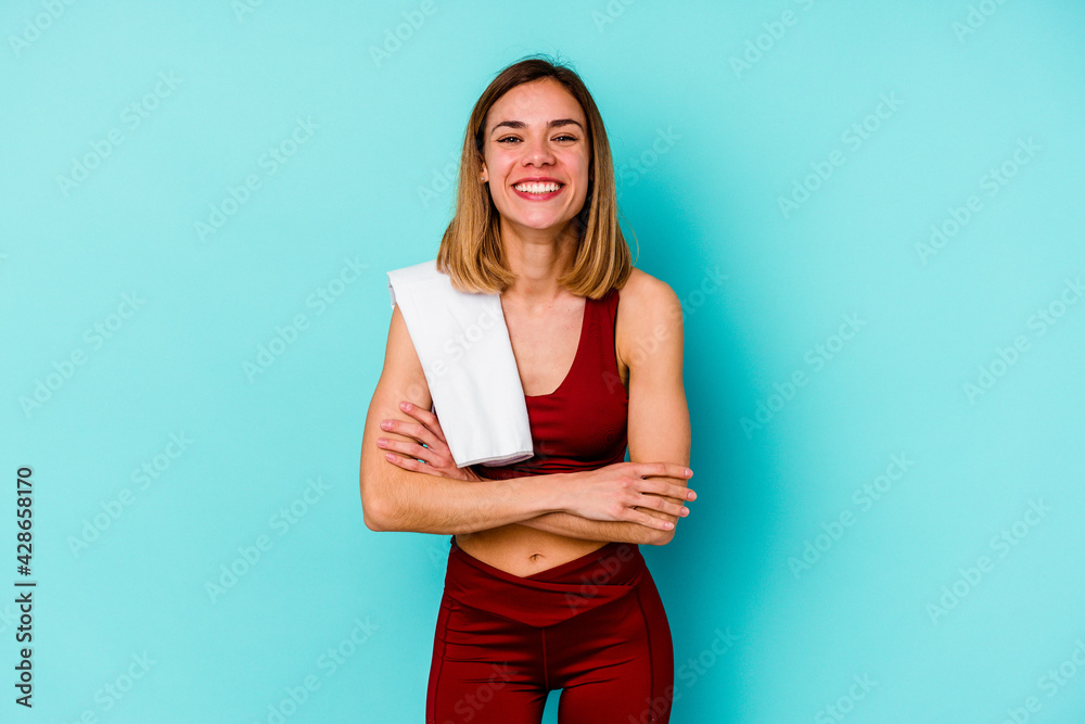 Young sport caucasian woman isolated on blue background laughing and having fun. Young sport caucasian woman isolated on blue background laughing and having fun.