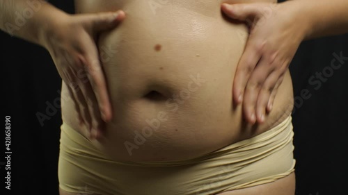 Wallpaper Mural Plus size girl massages stomach rubbing body cream on black background. Torontodigital.ca