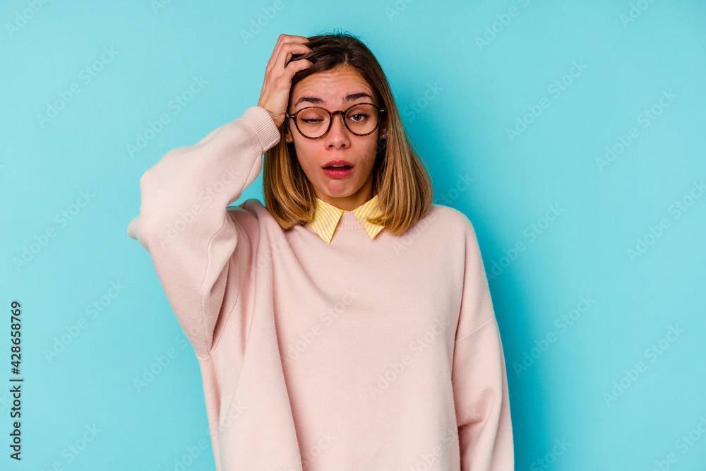 Fototapeta premium Young student caucasian woman isolated on blue background tired and very sleepy keeping hand on head.