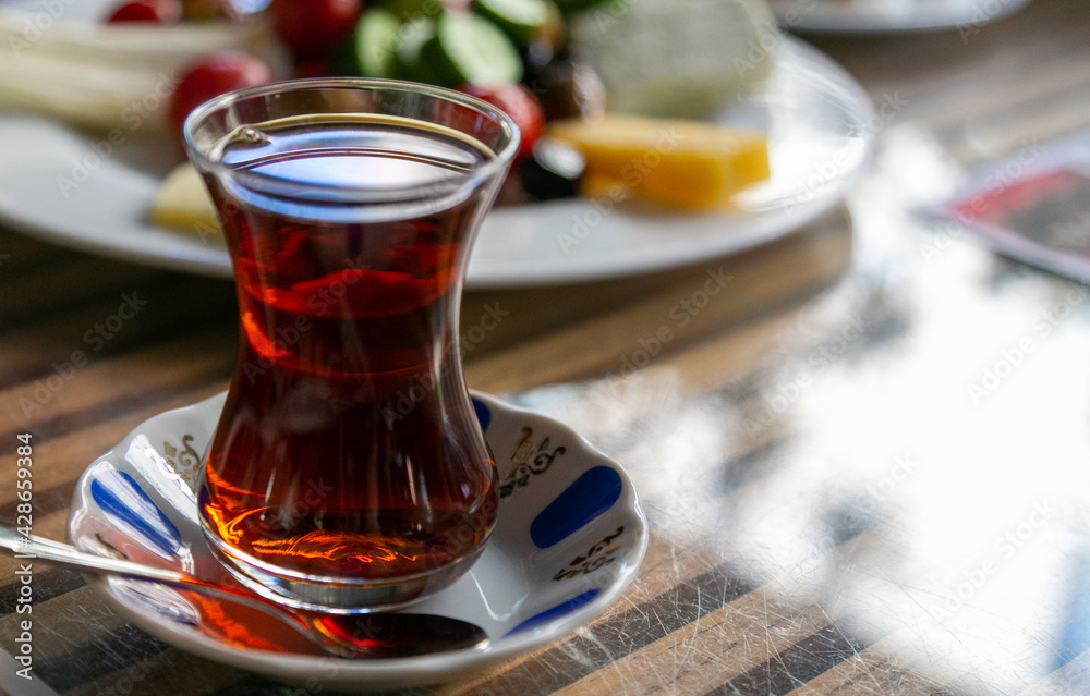 Turkish red aromatic tea in traditional authentic glass cup - armudu on table close-up with blurred dish in background. Brewing tea is an indispensable pleasure for Turks, photo with copy space area Turkish red aromatic tea in traditional authentic glass cup - armudu on table close-up with blurred dish in background. Brewing tea is an indispensable pleasure for Turks, photo with copy space area