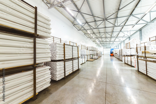 Spacious light interior of a large warehouse in a factory with special racks and shelves and products placed on them.