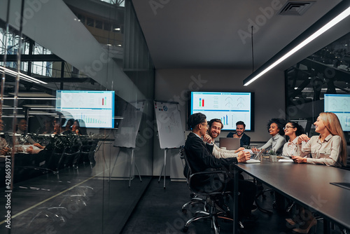 Group of successful smiling business people discussing work in a spacious conference office. Presentation. Data analysis, statistics, finance.Business team.Copy space.