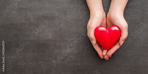 The woman is holding a red heart.