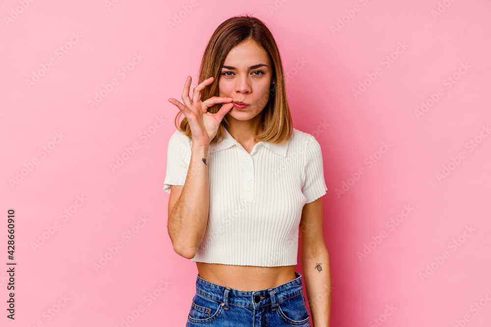 Young caucasian woman isolated on pink background with fingers on lips keeping a secret.