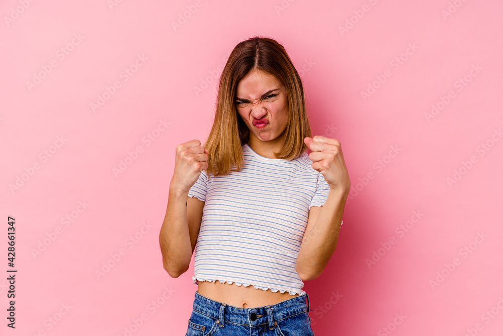 Young caucasian woman isolated on pink background showing fist to camera, aggressive facial expression. Young caucasian woman isolated on pink background showing fist to camera, aggressive facial expression.