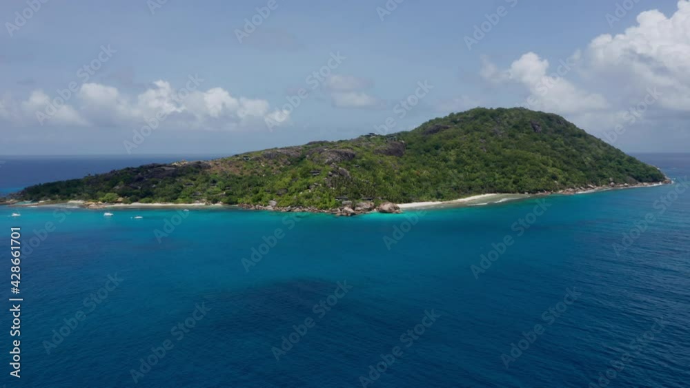 Wide aerial shot of tropical island exotic vacation destination. Sunny day with white sand beaches and palm trees. Drone flies over turquoise blue ocean water and relaxing waves to honeymoon island. Wide aerial shot of tropical island exotic vacation destination. Sunny day with white sand beaches and palm trees. Drone flies over turquoise blue ocean water and relaxing waves to honeymoon island.
