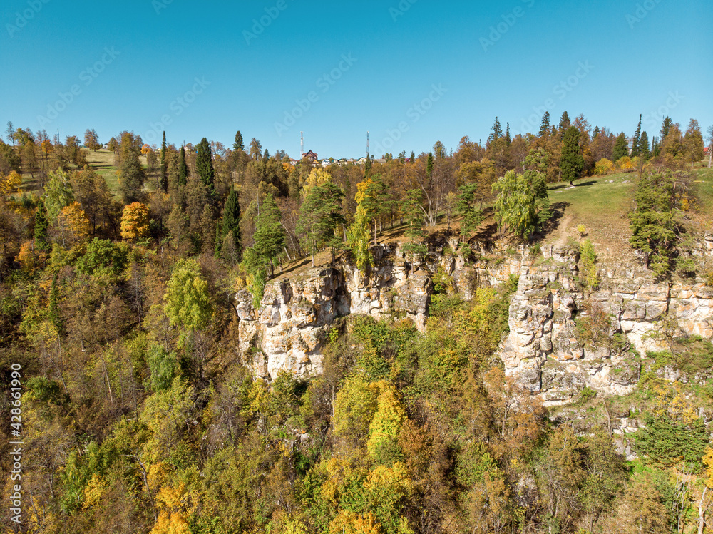 Observation platform Red Rocks near the Pavlovsk reservoir. Autumn forest and trees growing on a karst cliff