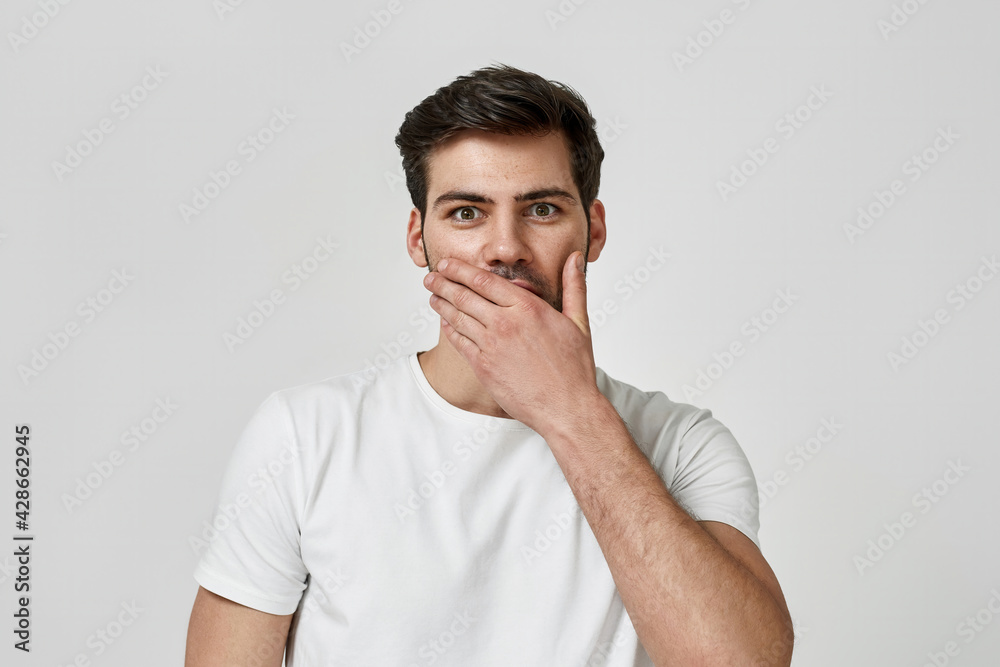 Man wearing t-shirt keeping hand on his lips