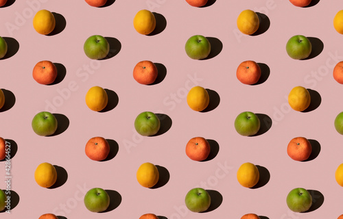 Bright colorful summer fruit pattern made with fresh green apple, lemon and mandarin orange or tangerine. Flat lay on pink pastel background, linear, geometric.