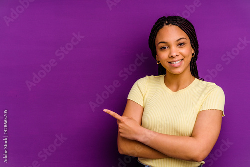 Young african american woman isolated on yellow background Young african american woman isolated on yellow background smiling cheerfully pointing with forefinger away.