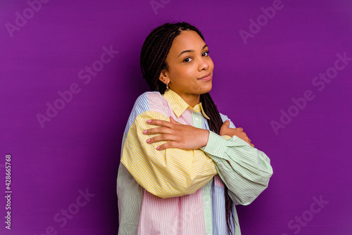 Young african american woman isolated on yellow background hugs, smiling carefree and happy.