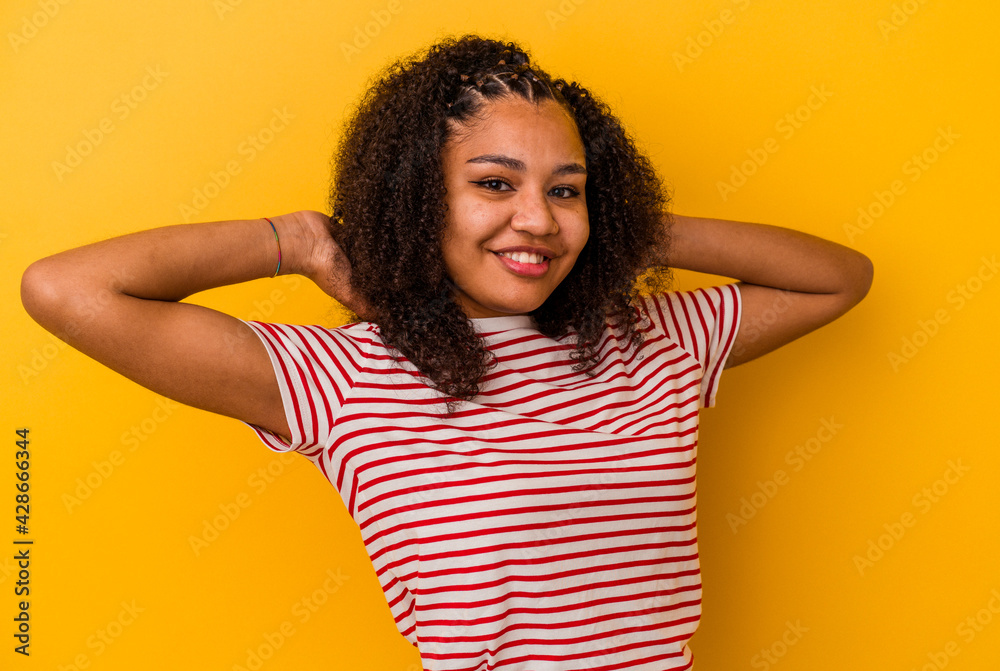 Young african american woman isolated on yellow background stretching arms, relaxed position. Young african american woman isolated on yellow background stretching arms, relaxed position.