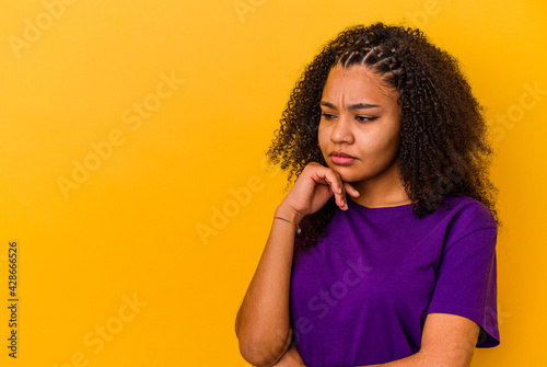 Young african american woman isolated on yellow background looking sideways with doubtful and skeptical expression.