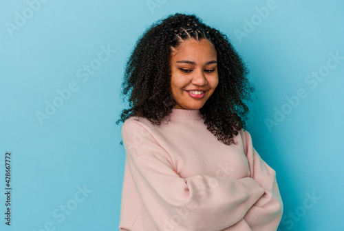 Young african american woman isolated on blue background smiling confident with crossed arms.