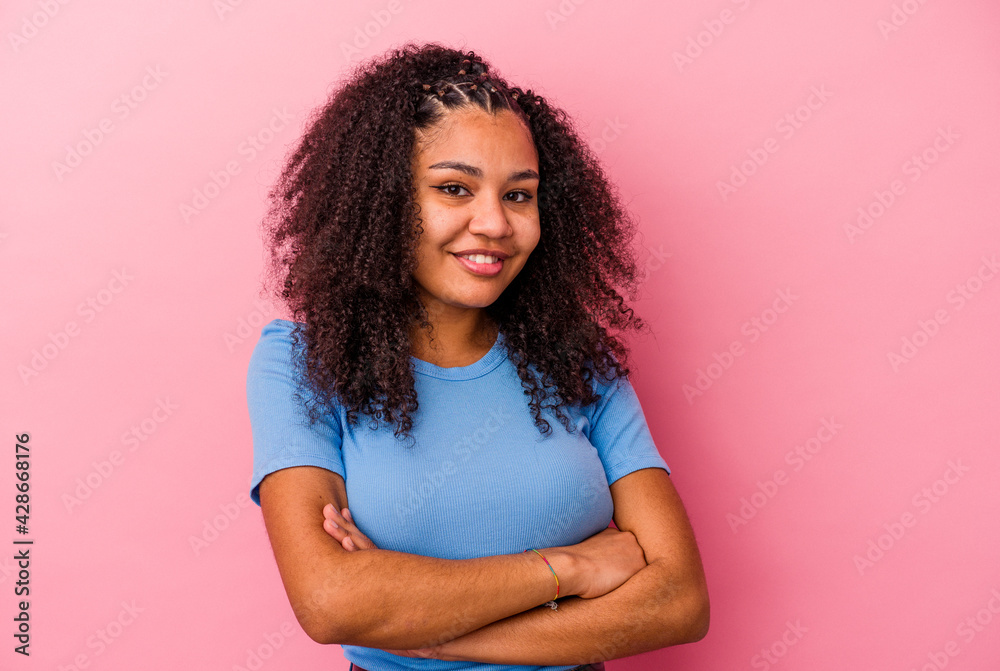 Young african american woman isolated on pink background who feels confident, crossing arms with determination. Young african american woman isolated on pink background who feels confident, crossing arms with determination.