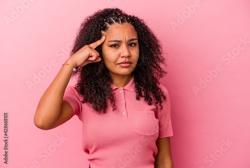 Young african american woman isolated on pink background pointing temple with finger, thinking, focused on a task.
