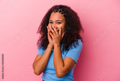 Young african american woman isolated on pink background laughing about something, covering mouth with hands.
