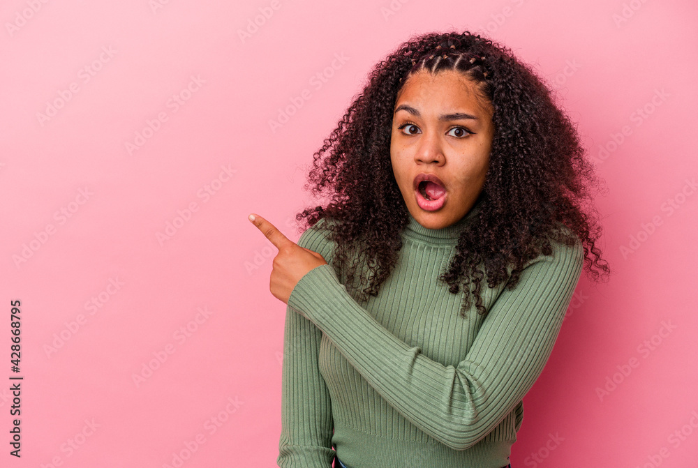Young african american woman isolated on pink background pointing to the side