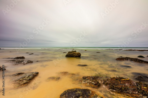 Long exposure horizontal photo, seashore with many small stones in the middle Three different stone sizes one after the other.