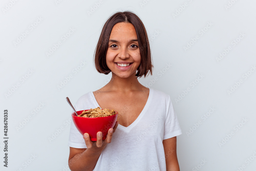 Young mixed race woman eating cereals isolated on white background happy, smiling and cheerful. Young mixed race woman eating cereals isolated on white background happy, smiling and cheerful.