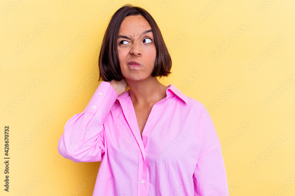 Young mixed race woman isolated on yellow background touching back of head, thinking and making a choice. Young mixed race woman isolated on yellow background touching back of head, thinking and making a choice.