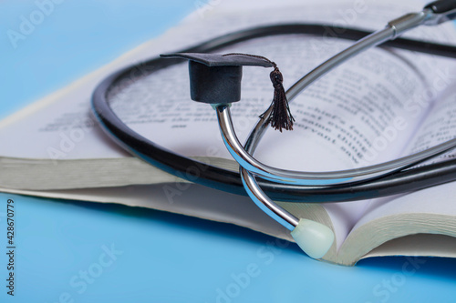 medical education. stethoscope, book and graduate hat. medical concept on blue background. graduate