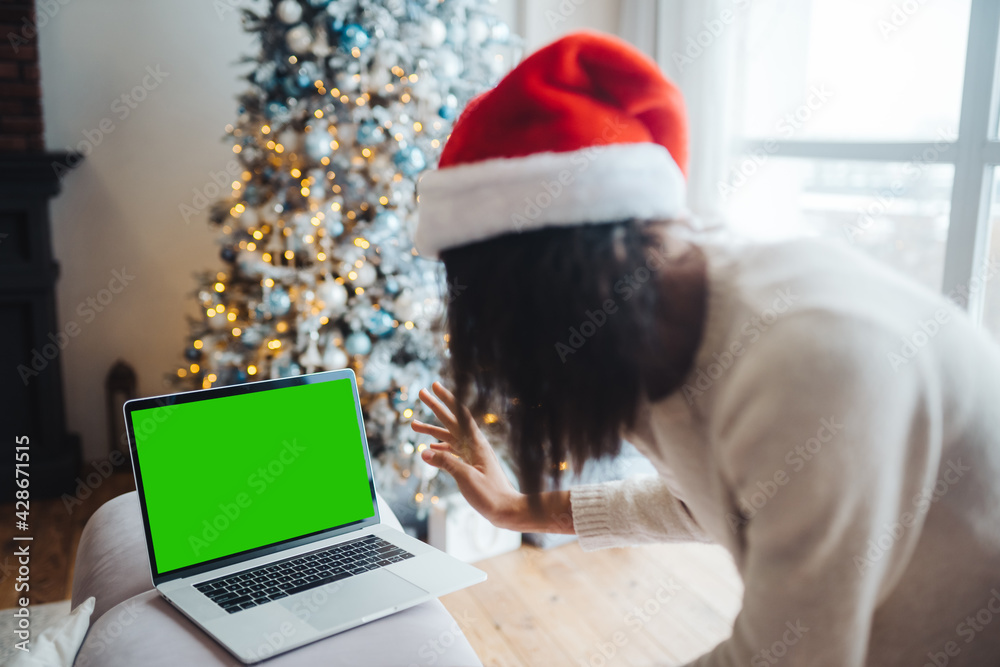 Female wearing santa hat while speaking with online friend on laptop Female wearing santa hat while speaking with online friend on laptop