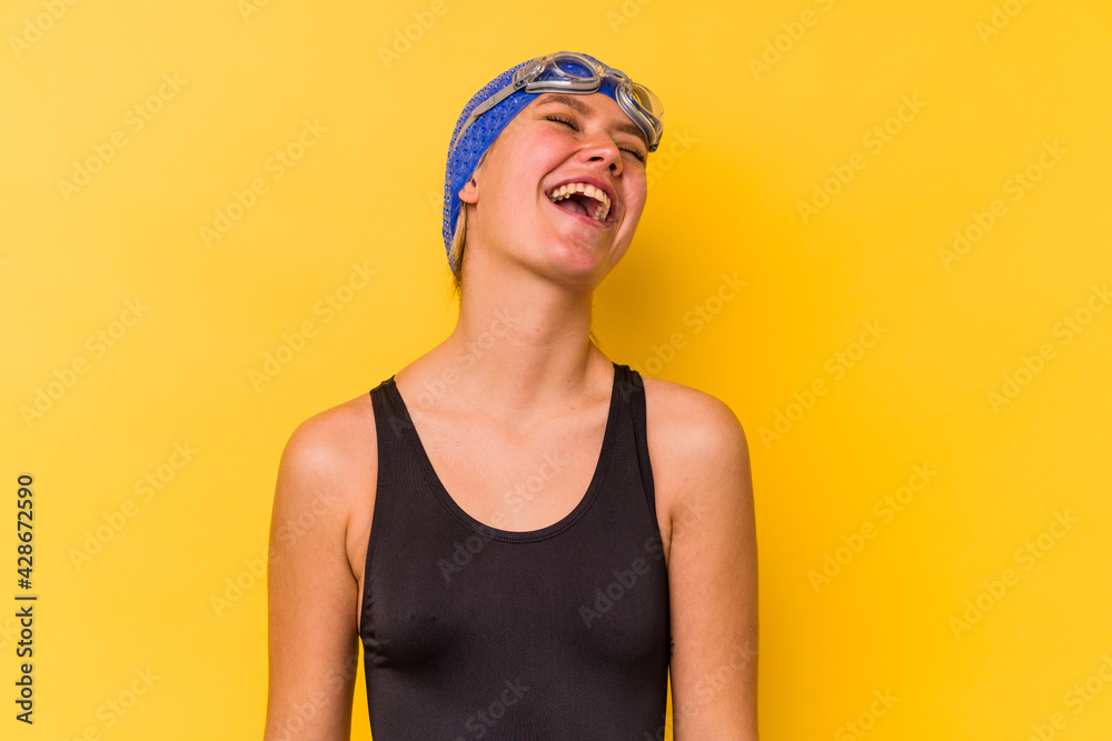 Young swimmer venezuelan woman isolated on yellow background relaxed and happy laughing, neck stretched showing teeth. Young swimmer venezuelan woman isolated on yellow background relaxed and happy laughing, neck stretched showing teeth.