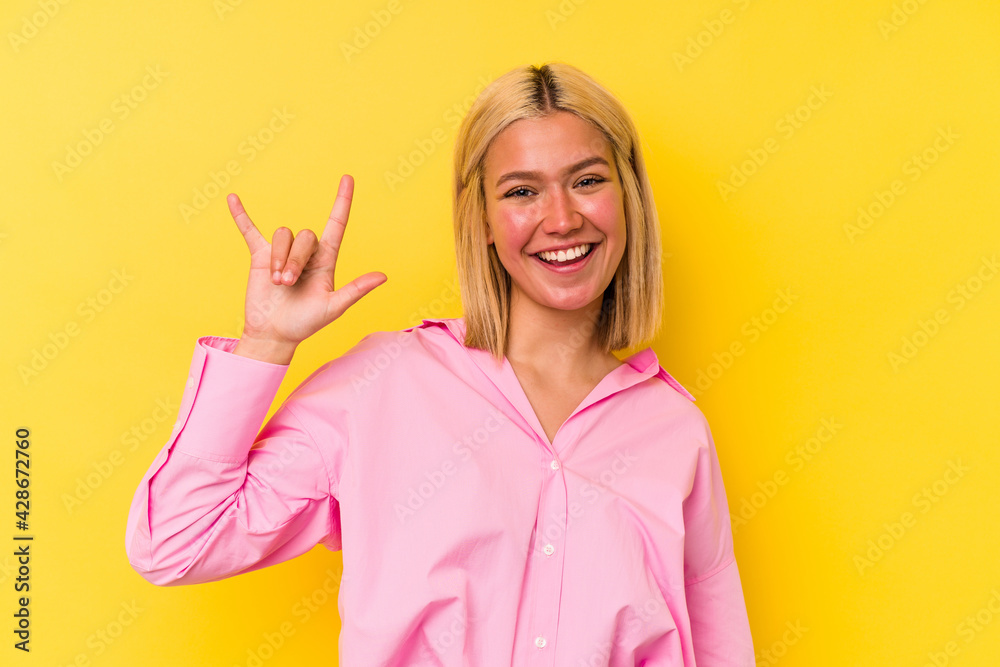 Young venezuelan woman isolated on yellow background showing a horns gesture as a revolution concept. Young venezuelan woman isolated on yellow background showing a horns gesture as a revolution concept.