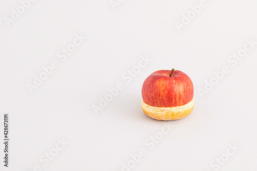 Creative food concept with half apple and half donut isolated on grey background