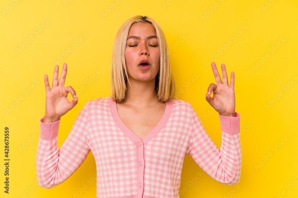Young venezuelan woman isolated on yellow background relaxes after hard working day, she is performing yoga.