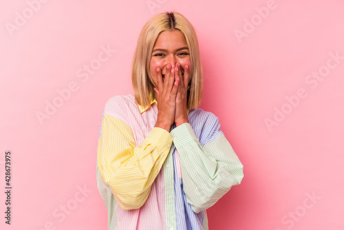 Young venezuelan woman isolated on pink background laughing about something, covering mouth with hands.