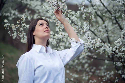 Portrait of beautiful young woman at spring in orchard