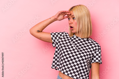 Young venezuelan woman isolated on pink background looking far away keeping hand on forehead.