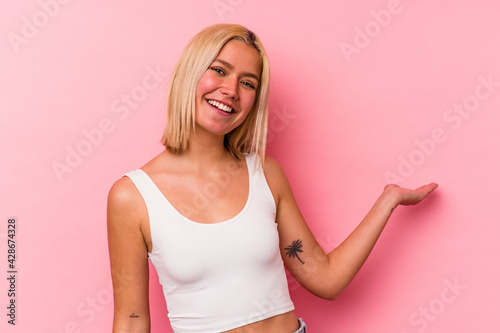 Young venezuelan woman isolated on pink background showing a welcome expression. © Asier