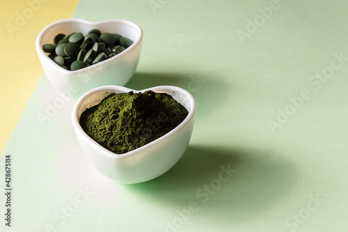Organic spirulina powder and pills in a heart shaped plate