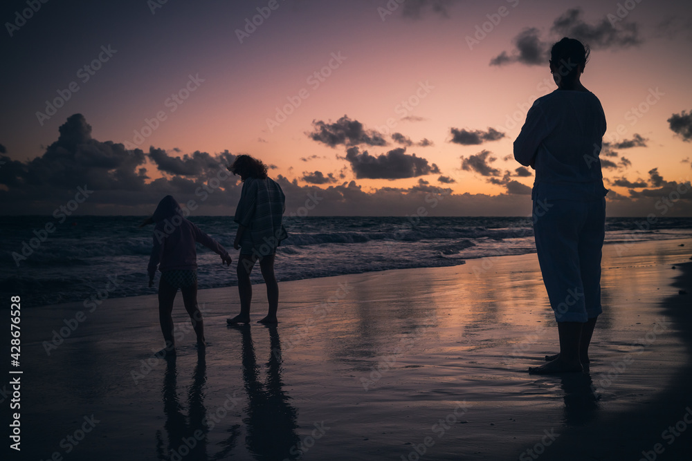 Silhouette photo of a mother with daughters walking on beach