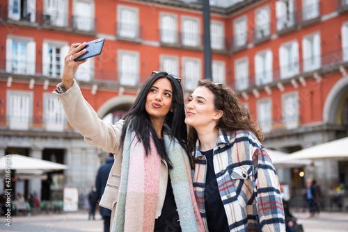 two tourist girls take a selfie in the central square of the city. Plaza Mayor  Madrid