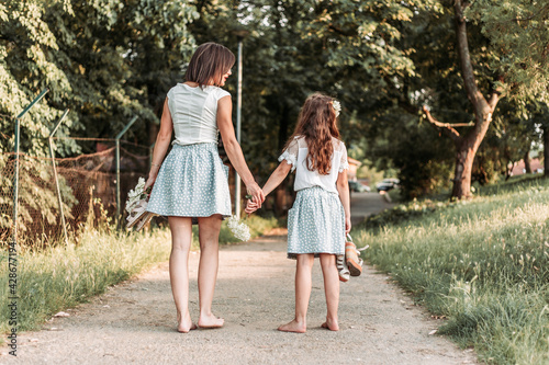 Mom and daughter in same outfit walking together down the road bare foot © stivog