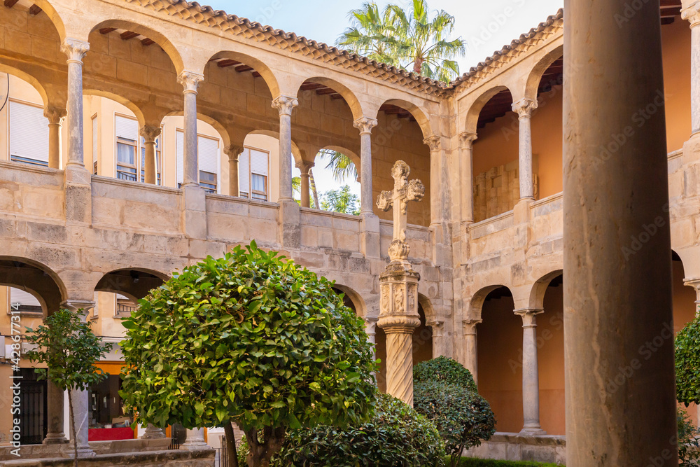 The courtyard of the Monastery of the Sacred Cathedral of El Salvador with a stone cross in the city of Orihuela on the Costa Blanca in Spain