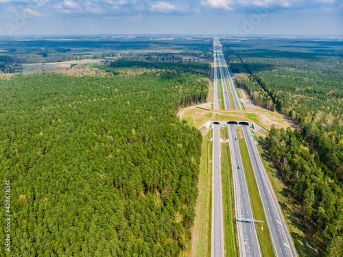 Expressway with ecoduct crossing - bridge over a motorway that allows wildlife to safely cross over the road, aerial top down view
