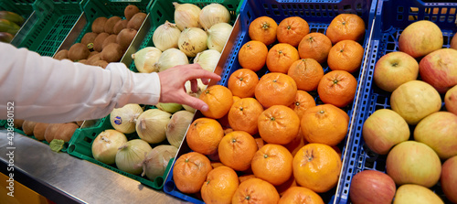 Fototapeta Naklejka Na Ścianę i Meble -  A hand grabbing an orange at a fruits and vegetable market